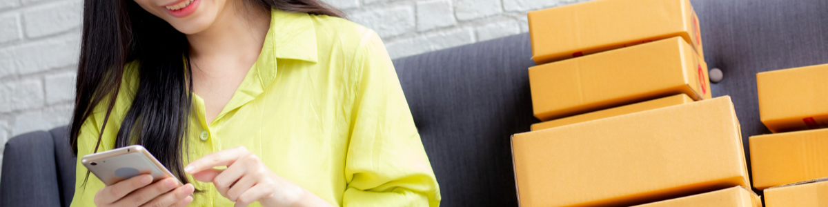 Asian woman in yellow blouse looking at cell phone in her hand