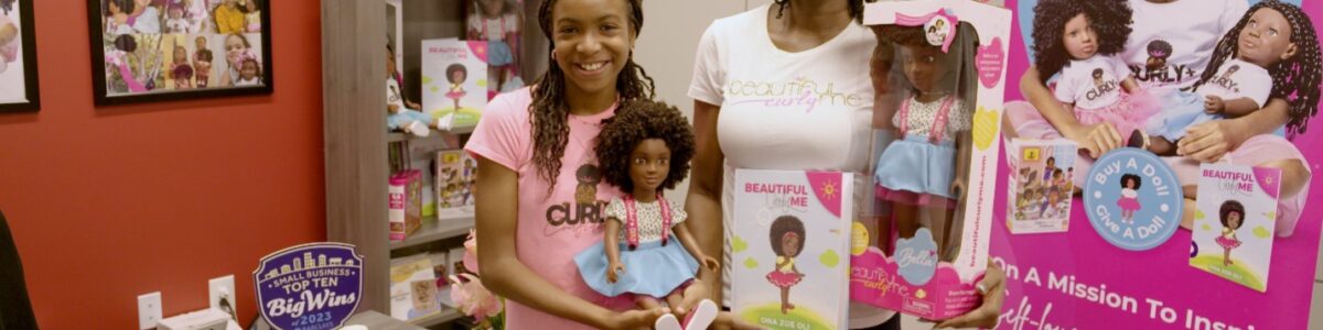 Black woman and young girl smiling and holding Black dolls.