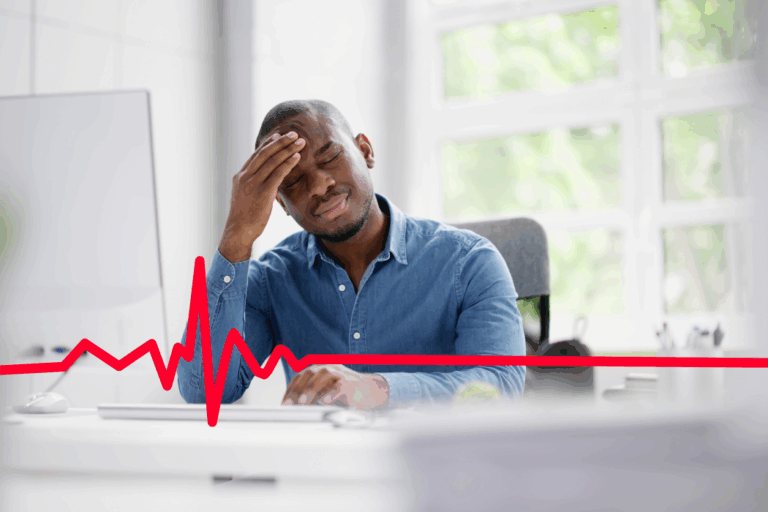Frustrated worker sitting at his desk with his hand on his forehead.