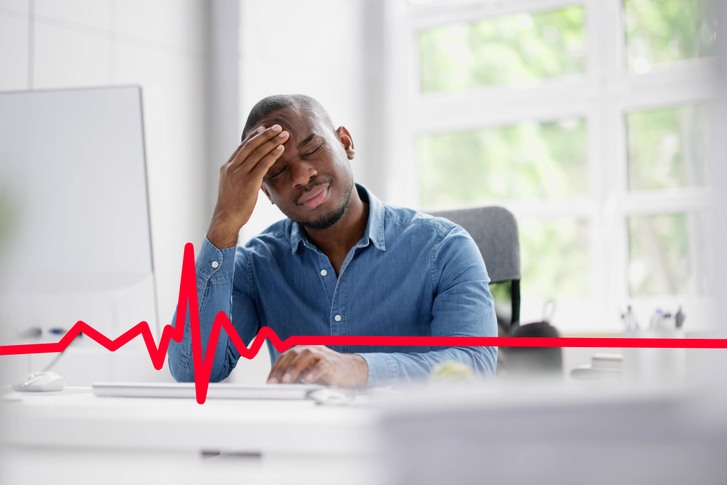 Frustrated worker sitting at his desk with his hand on his forehead.