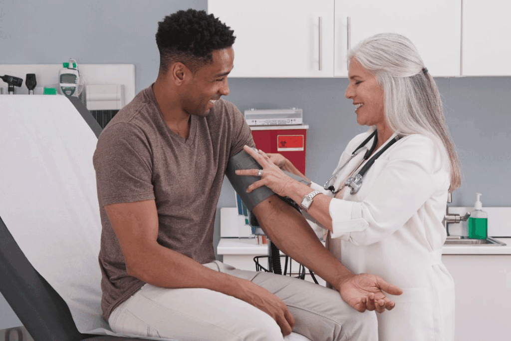 Young Black man getting his blood pressure checked by older nurse.