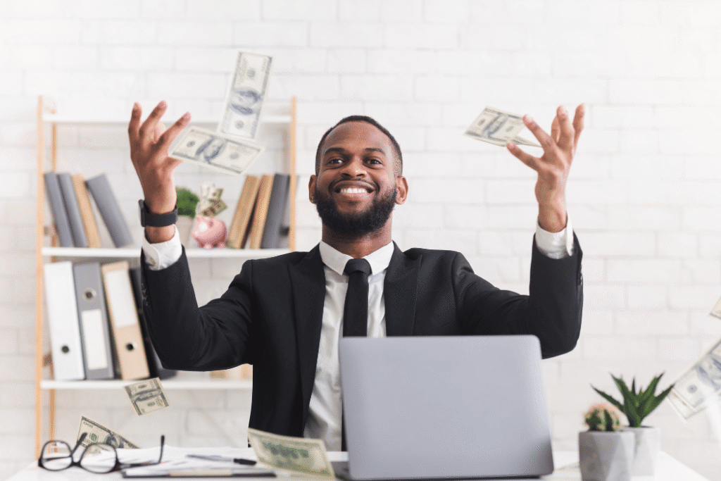 Man sitting at desk throwing money in the air