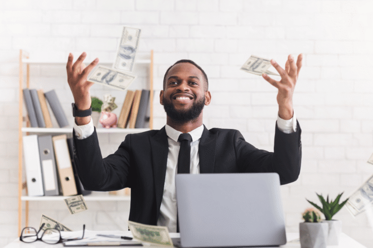 Man sitting at desk throwing money in the air