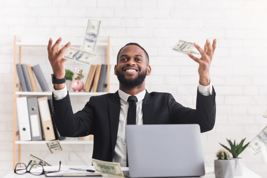Man sitting at desk throwing money in the air