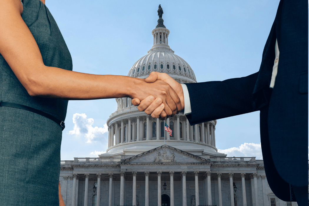 Two people shaking hands with the U.S. Capitol in the background