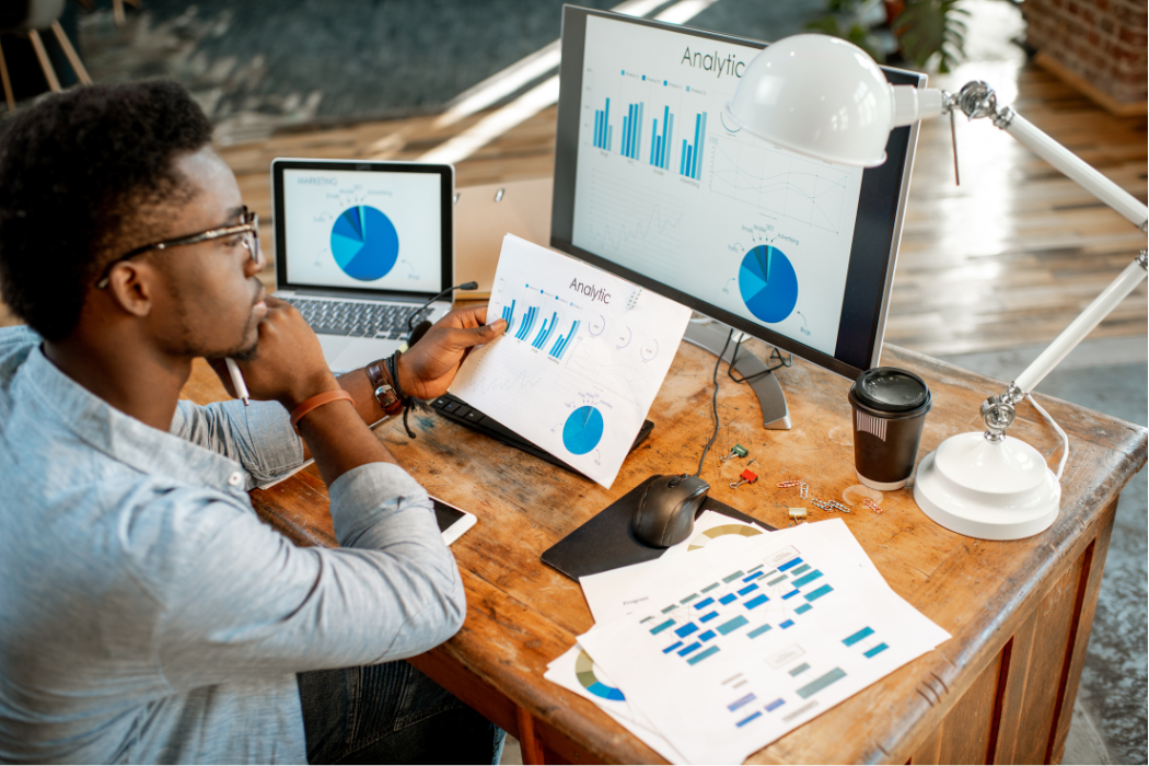 Black man sitting at desk reading economic graphs