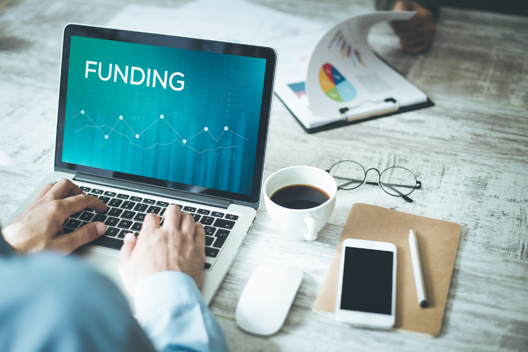 Photo of back of businessman sitting at computer with Funding on the screen