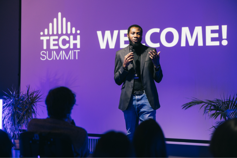 Young Black man stands on stage presenting at a tech summit