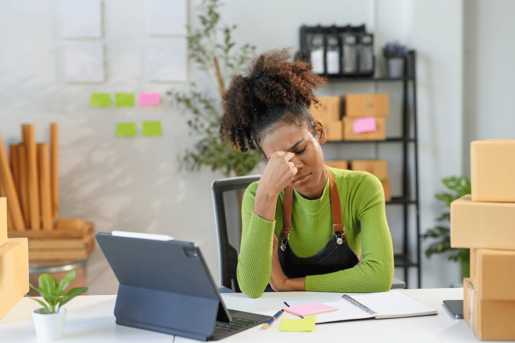 Woman stressed out holding her head in hand while sitting at her desk