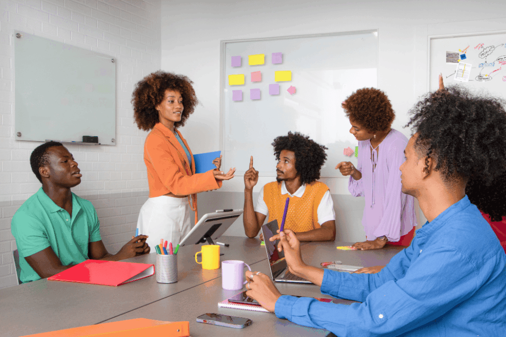 Black woman with an afro standing at whiteboard teaching colleagues
