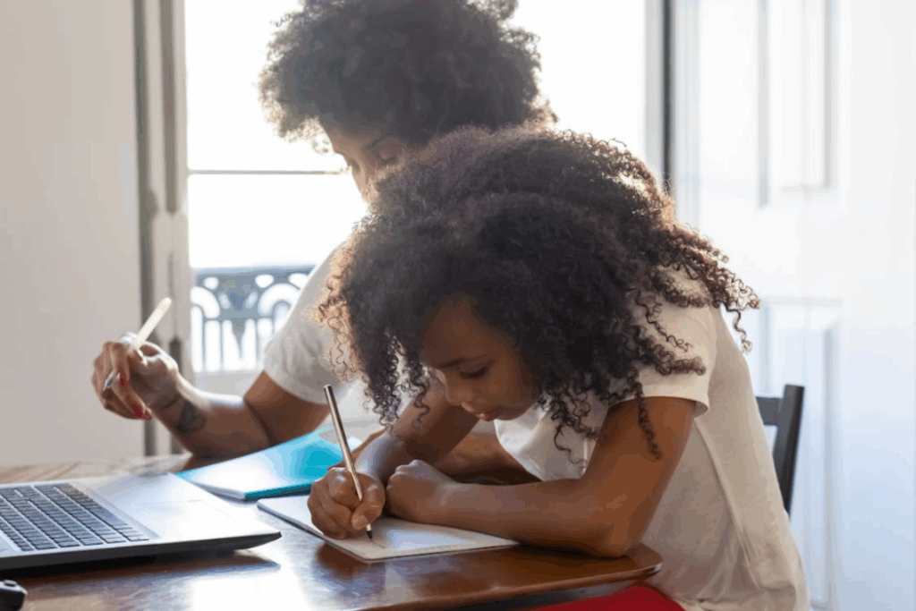Two Black students sitting at a desk together with their heads down studying
