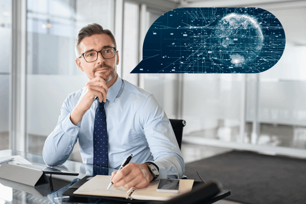 Latino businessman sitting at desk thinking about AI in thought bubble above him.