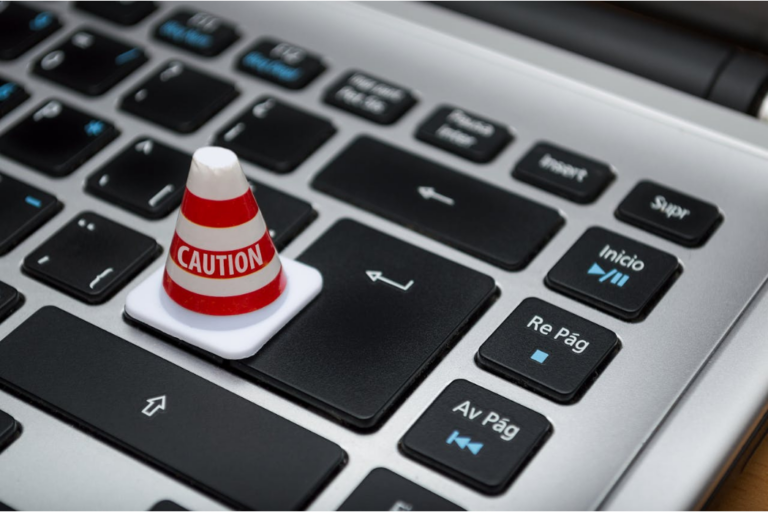 Miniature red and white caution cone on a laptop keyboard