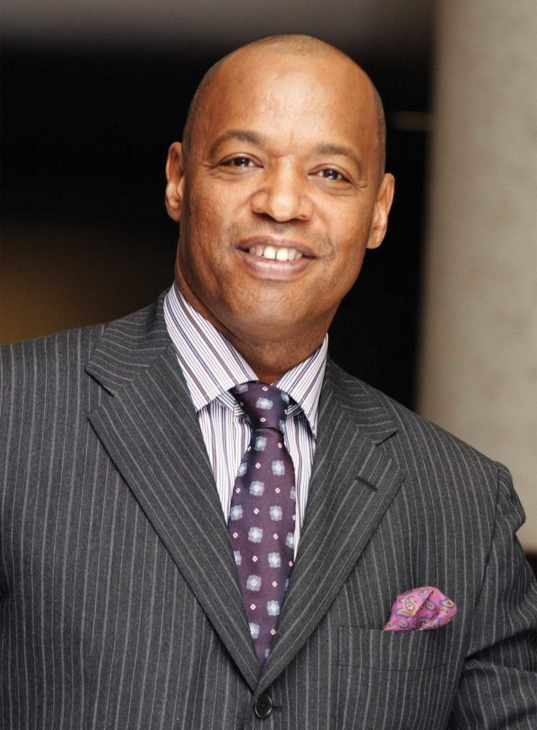 Bald Black man with gray suit and purple striped shirt