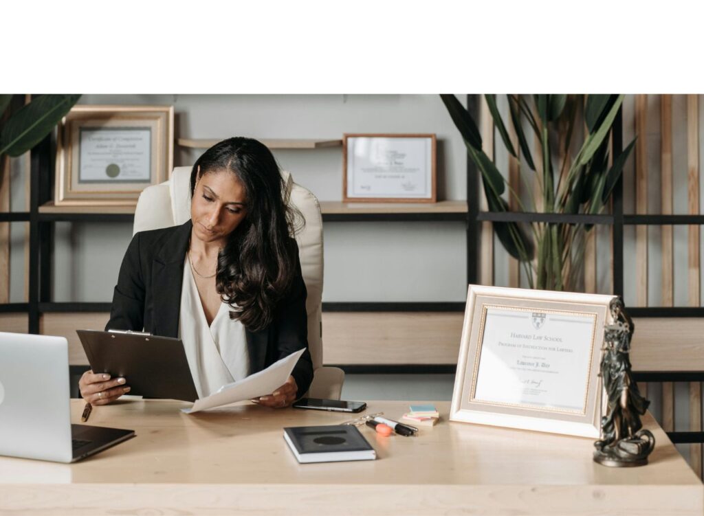 Woman sitting at desk with laptop writing.