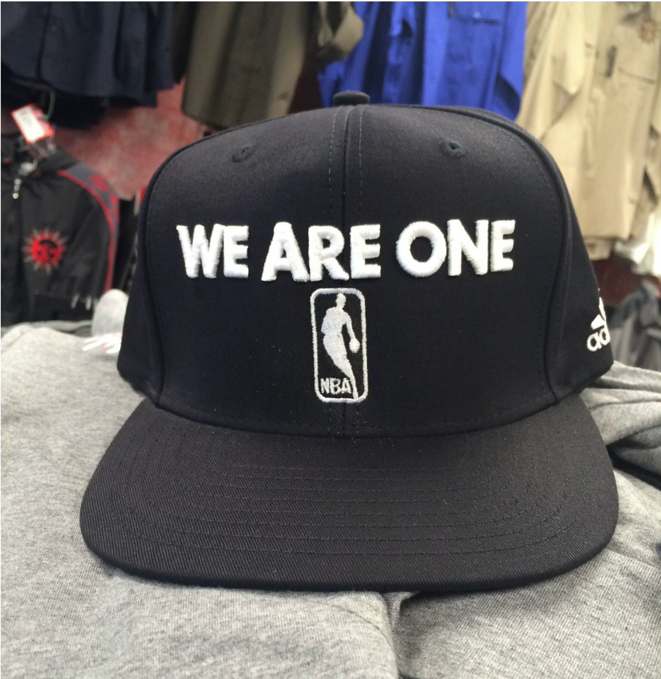A black baseball cap with the words We Are One above the NBA logo on display.